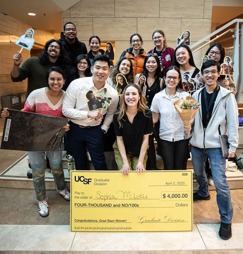 Sophia Miliotis, 1st prize winner of 2025 UCSF Grad Slam, poses with giant check, flanked by fellow students and colleagues