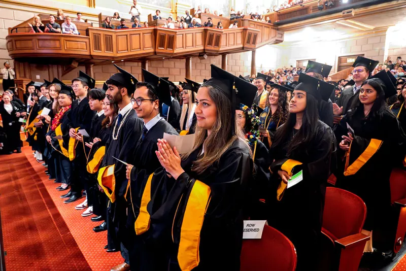 master's candidates applaud in the audience at commencement