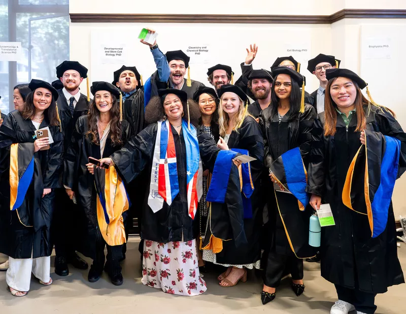 a group of phd students in regalia pose for a celebratory photo