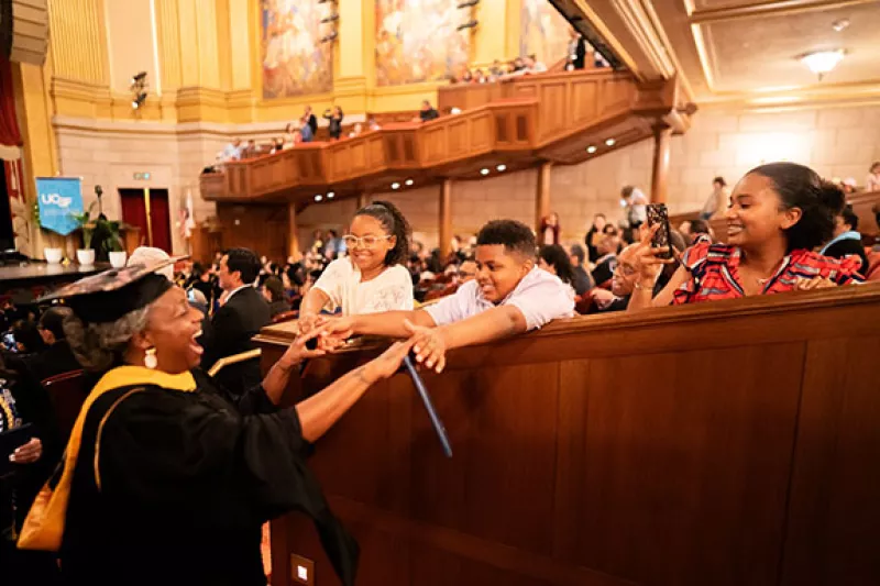 A new grad greets family members during commencement recessional.