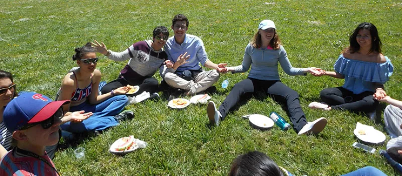 Students sitting on the grass eating several students sit in the grass enjoying a picnic