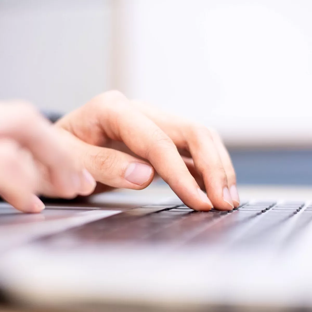 Fingers typing on a laptop