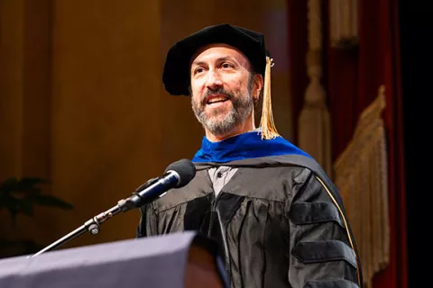 Mark Ansel speaks at podium in academic regalia