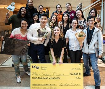 Sophia Miliotis, 1st prize winner of 2025 UCSF Grad Slam, poses with giant check, flanked by fellow students and colleagues