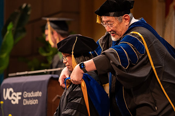 a faculty member hoods a graduate at commencement