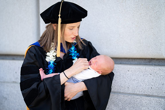 A new grad cradles an infant