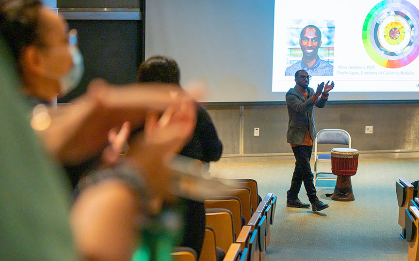 Dr. Adisa Anderson leads audience members in a clapping activity.