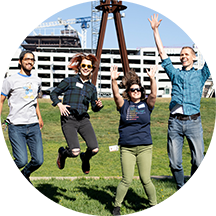 four people jump in the air on the campus quad