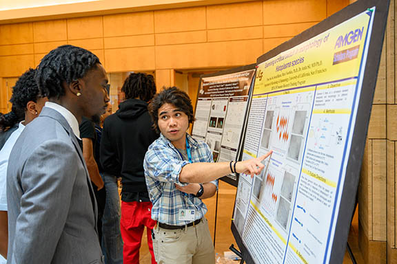 an Amgen Scholar presents their poster to attendees at the SRTP symposium in 2023