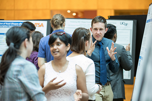 students explain their research at a poster session