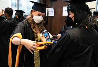 PhD grads in academic regalia get ready backstage before the ceremony